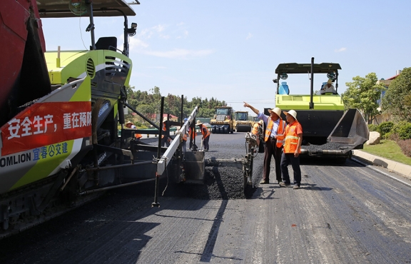攤鋪機(jī)、壓路機(jī)等設(shè)備緊張有序運(yùn)行，高達(dá)170℃的瀝青混合料炙烤著公路人